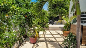 Un jardín con diversas plantas y un patio amueblado con mesa y sillas.