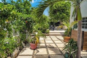 Ein Garten mit verschiedenen Pflanzen und einer Terrasse mit Tisch und Stühlen.