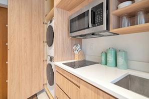 Eine kleine Küche mit Mikrowelle, Herd und Spüle. Holzschränke und eine Arbeitsplatte sind vorhanden.
