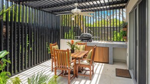 Un patio cubierto con mesa y sillas, una parrilla y un ventilador de techo.