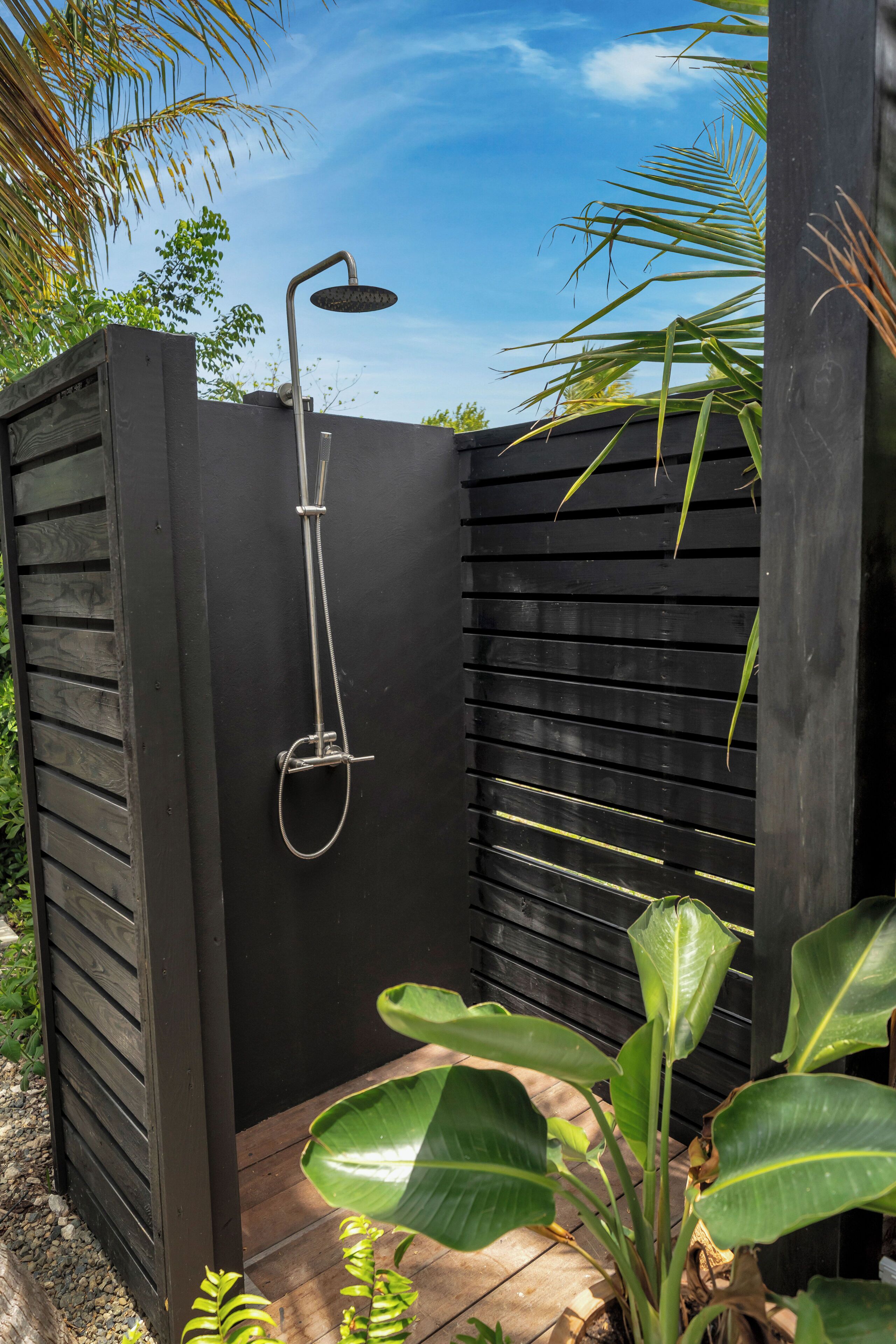 A black metal shower enclosure with a rain shower head and hose.