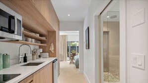 Una cocina moderna con armarios de madera, microondas integrado y un lavamanos.