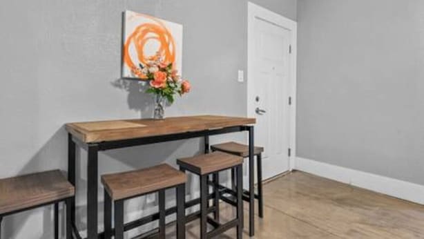A small room with a wooden table and two stools, a white door, and a wall-mounted painting. - Comfortable stay in historic Sherman Hill-3 (Des Moines)