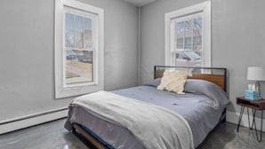 A bedroom with a bed, a nightstand, and two windows. - Comfortable stay in historic Sherman Hill-3 (Des Moines)