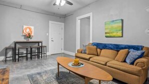 A living room with a sofa, coffee table, and a dining area with chairs and a table. - Comfortable stay in historic Sherman Hill-3 (Des Moines)