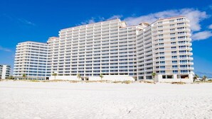 Ein großes, mehrstöckiges Hotel mit symmetrischer Fassade, gelegen an einem sandigen Strand unter klarem Himmel.