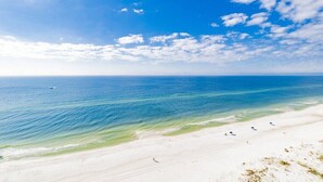 Ein Strand mit klarem, blauem Wasser und weißem Sand, mit einigen Sonnenschirmen.