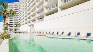 Ein Swimmingpool mit Liegestühlen und einem Hochhaus im Hintergrund.