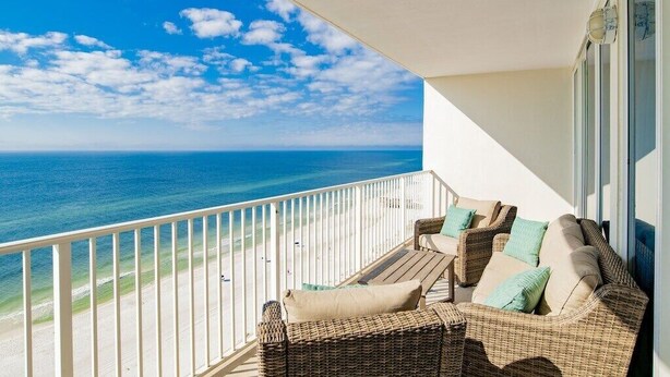 Ein Balkon mit Korbmöbeln und Blick auf das Meer.