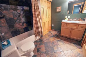 Een badkamer met een wit toilet, een houten kast en een douchegedeelte met een ruitjes gordijn.