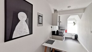 Une cuisine moderne avec des meubles blancs, un plan de travail noir et un coin repas comprenant une table et un banc blancs.