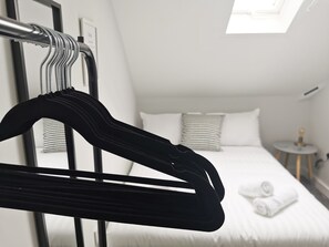 Ein Hotelzimmer mit einem Bett, einem Nachttisch und einer Kleiderstange.