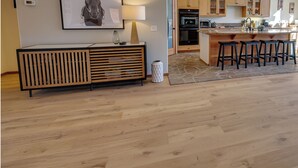 Una cocina moderna con armarios de madera, una isla central con taburetes y horno empotrado, además de un microondas.