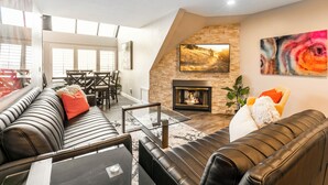A modern living room with a fireplace, leather sofas, and a dining area with a glass table.