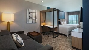 Een hotelkamer met een bank, een bureau, een bed en een groot raam.