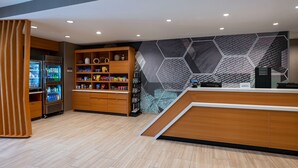 Een modern receptiegebied met een houten balie, een gekoelde displaykast en een wand met een honingraatpatroon.