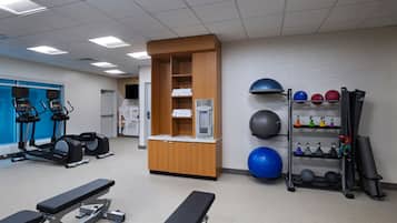 A gym with treadmills, a bench, exercise balls, and a rack of dumbbells.