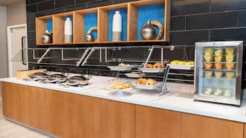 A buffet setup with various food items and a beverage dispenser.