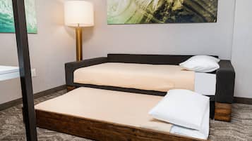 Een hotelkamer met een bed, nachtkastje, lamp en een schilderij aan de muur.