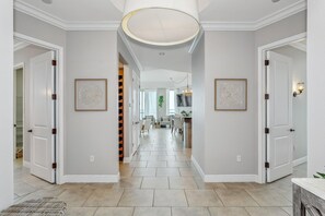 A spacious hallway with white walls, a tiled floor, and framed artwork.