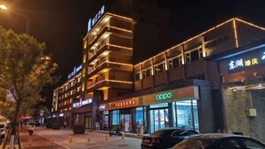 Un hotel de varios pisos con señalización iluminada, incluyendo una tienda 'Oppo' en la planta baja.