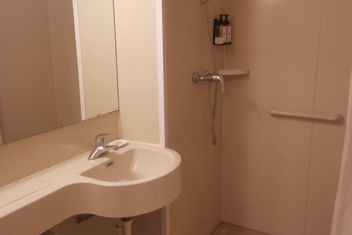 A bathroom with a white sink, a mirror, and a shower.