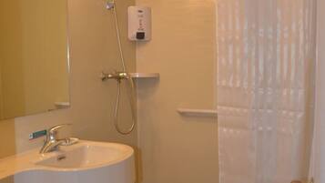 Un baño con lavabo, espejo, ducha y toallero.