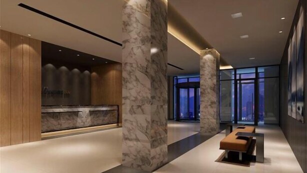 Un vestíbulo moderno con columnas de mármol, un mostrador de recepción y un banco.