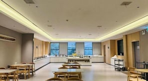 A spacious dining area with tables and chairs, a kitchen counter, and large windows.
