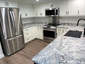 A modern kitchen with stainless steel appliances, white cabinets, and a granite countertop.