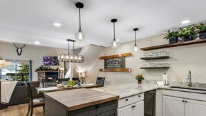 Une cuisine moderne dotée d’un îlot central, de meubles en bois et de luminaires suspendus.