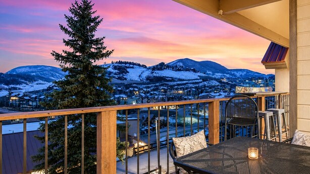 Un balcon offrant une vue sur des montagnes enneigées et sur une ville située en contrebas.