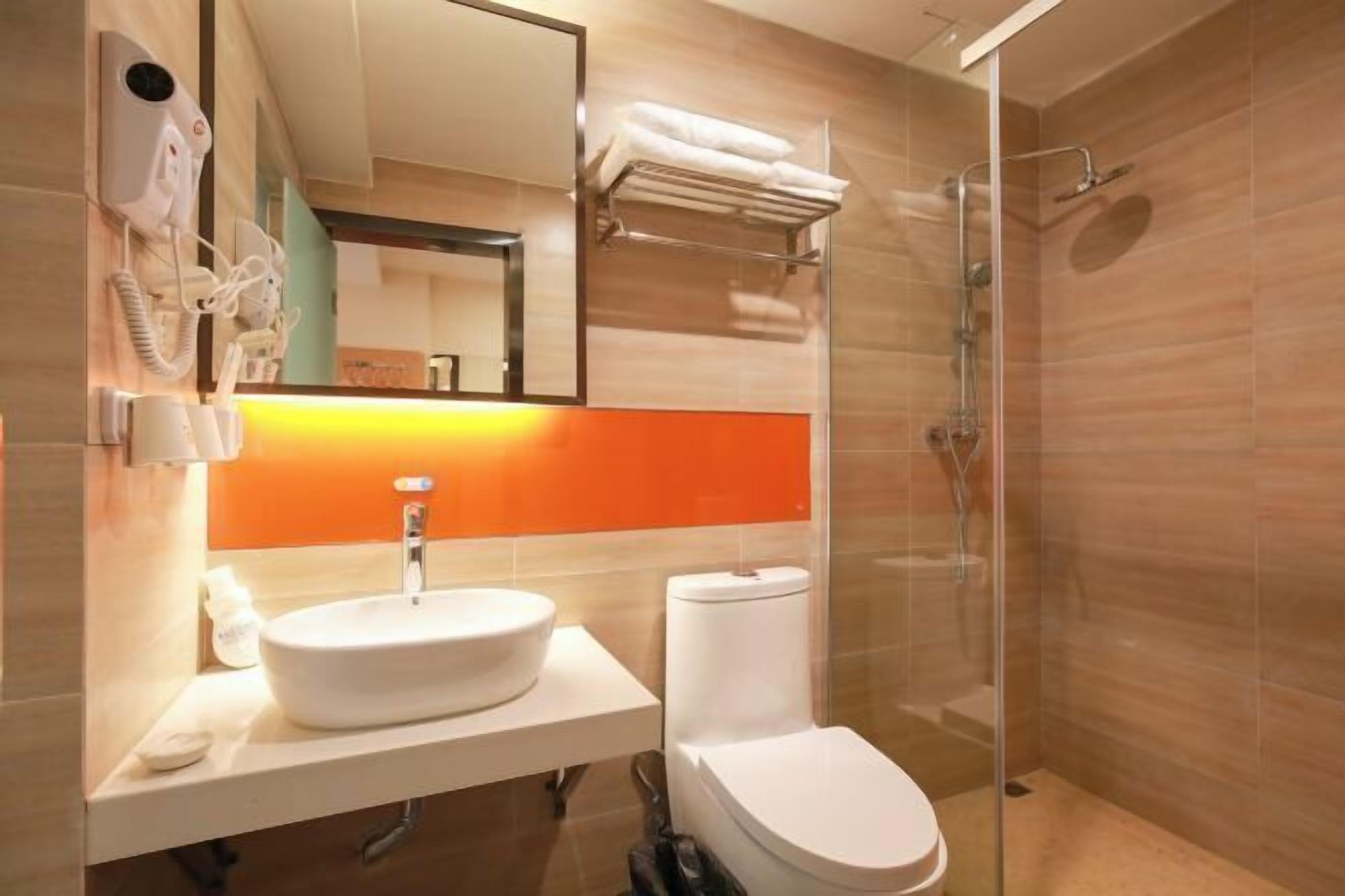 A modern bathroom with a glass-enclosed shower, a white sink, and a toilet.