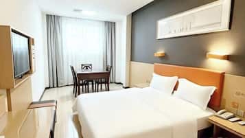 A hotel room with a large bed, a desk, and a television.