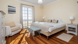 A bedroom with a bed, bedside tables, a bench, a sofa, and a window.