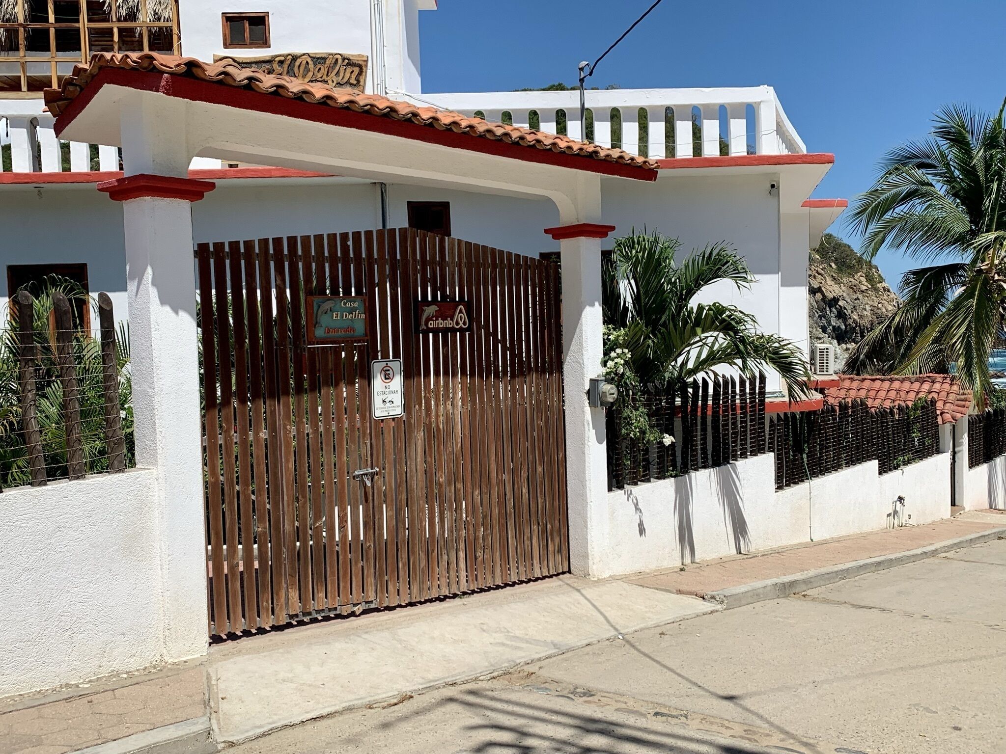 A gated property with a white exterior, red roof, and a wooden fence.