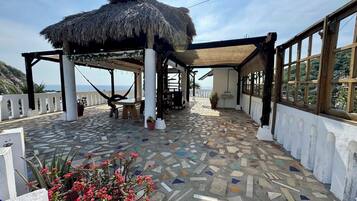 Un espace extérieur abrité, doté d’un toit de chaume, d’un sol recouvert de mosaïques et offrant une vue sur la mer.