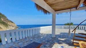 A covered outdoor area with a patterned floor, wooden furniture, and a view of the ocean. - Casa El Delfin, 3rd Floor Bungalow - Estacahuite (Estacahuite)