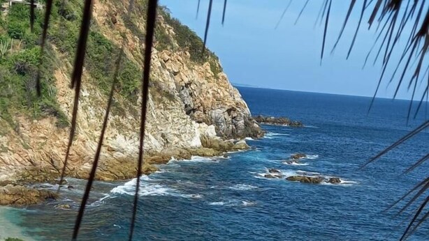A coastal beach with clear blue waters, rocky cliffs, and a sandy shore. - Casa El Delfin, 3rd Floor Bungalow - Estacahuite (Estacahuite)