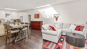 Ein stilvoller Wohnbereich mit Essplatz, einer Couch, einem Couchtisch und einer Küche im Hintergrund.