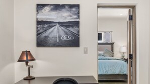 Ein Schlafzimmer mit einem Bett, einem Nachttisch, einer Lampe und einem an der Wand befestigten Fernseher.