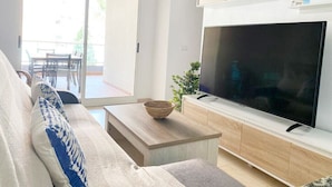 Een moderne woonkamer met een bank, een salontafel en een flatscreen televisie op een houten kast.