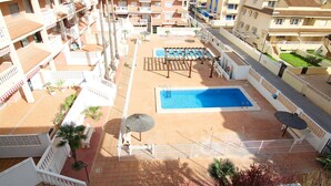 Un área de piscina en la azotea con una piscina rectangular, tumbonas y una pérgola.