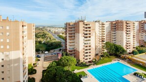 Ein Hochhaus mit mehreren Balkonen, einem Schwimmbad und Blick auf eine Stadtlandschaft.