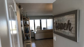 A living room with a sofa, a ladder, and a wall with a 'love you to the back' sign. - SANDCASTLES OCEAN VIEW TOP FLOOR..DATES AVAILABLE (check Reviews) (Cocoa Beach)