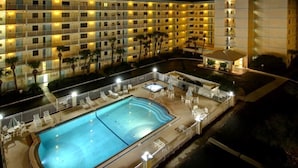 A hotel with a large outdoor swimming pool, multiple balconies, and a well-lit exterior. - SANDCASTLES OCEAN VIEW TOP FLOOR..DATES AVAILABLE (check Reviews) (Cocoa Beach)