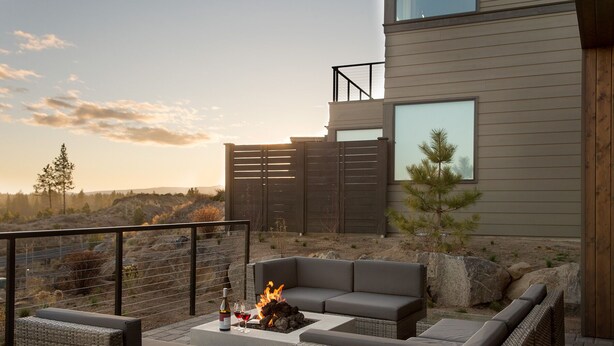 Un espacio al aire libre moderno con una chimenea, un sofá y una mesa.