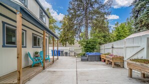 Een overdekt terras met buitenmeubilair, een barbecue en een houten terras.