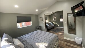 Een slaapkamer met een bed, een aan de muur bevestigde televisie, een raam en een spiegel.