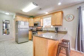 Enjoy cooking in this kitchen with a central island, bar stools, and stainless steel appliances.
